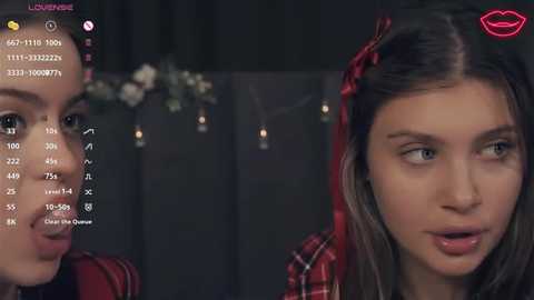 Media: A video of two young women, one with long brown hair and red plaid shirt, the other with light skin, dark hair, and a floral crown, both in a dimly lit room.