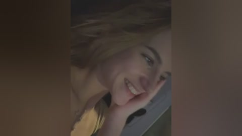 Media: Video of a smiling, fair-skinned woman with light brown hair, lying on her side, partially covered by a blurred, dark figure.