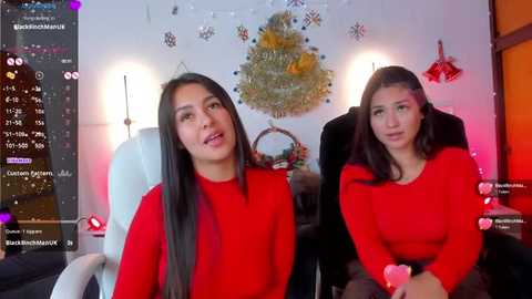 Media: Video of two young women with long dark hair, wearing red sweaters, seated in a gaming chair in a festive, well-lit room with holiday decorations.