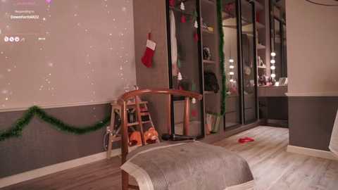 Media: A festive, well-lit bedroom with a wooden chair, green garland, red stockings, and a cozy, beige-covered ottoman.