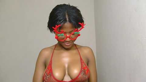 Media: A video of a dark-skinned woman with short black hair, wearing a red lace bra revealing ample cleavage, adorned with red reindeer antlers on her head.