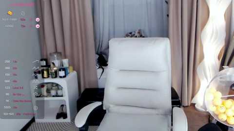 Media: A video of a modern, minimalist living room with a white leather recliner, beige curtains, a decorative table with yellow lemons, and a white bookshelf filled with various items.