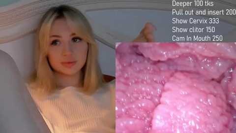 Media: Video of a blonde Caucasian woman in a beige sweater, lying on a bed with a white headboard. Close-up of her cervix, showing pink, soft, and slightly swollen tissue.