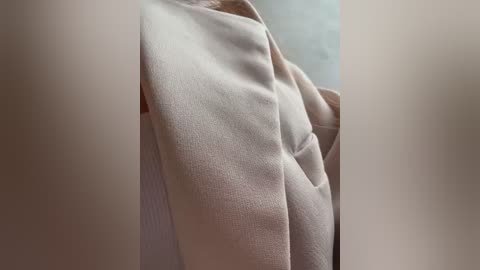 Media: A video showing a close-up of a woman's bare right breast, partially covered by a beige towel, with a blurred background.