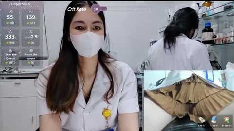 Media: Video of a young Asian woman in a white lab coat and face mask, sitting at a desk with a computer screen displaying medical data. Inset: another woman in a lab coat and brown skirt, bent over a desk, exposing her buttocks.