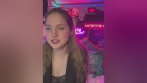 Media: A video of a young woman with long, wavy brown hair, fair skin, and red lipstick, wearing a black top, sitting in a brightly lit room with neon lights and colorful decor.