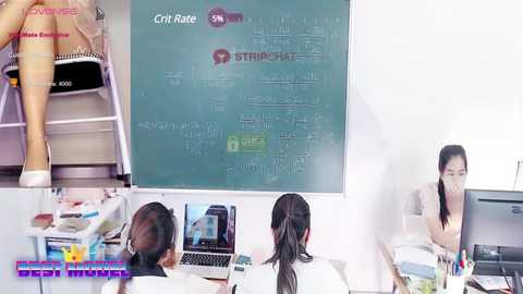 Media: A video showing an office scene with a teacher explaining a math problem on a whiteboard, students working on laptops, and a woman in a white top and black hair, with a close-up of legs in pink tights.