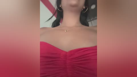 Media: A video of a woman in a red off-the-shoulder dress, wearing large gold hoop earrings. Her fair skin and black hair are partially visible. The background is blurred, focusing on her upper body and neck.