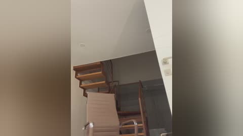 Media: Video of a modern, minimalist room with a beige sofa and wooden staircase leading to a loft, featuring a minimalist design with neutral tones and a sleek, contemporary aesthetic.