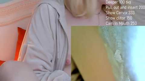 A close-up video of a blonde woman's partially unzipped light grey sweater, revealing her exposed nipple, taken from a low angle. Text overlay mentions deep throat, pull-out, and insert options.