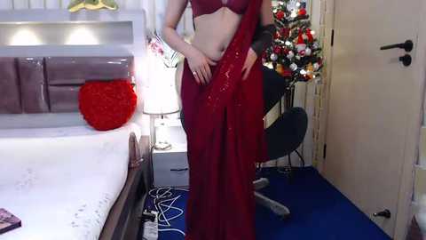 Media: Video of a woman in a red saree, standing in a modern bedroom with a Christmas tree and heart-shaped decorations.