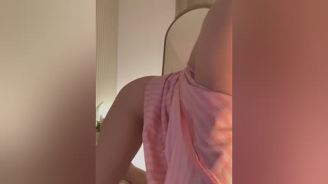 Media: Video of a fair-skinned woman in pink pajamas, bent over, showcasing her bare buttocks, taken indoors with soft lighting.