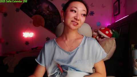 Media: A video of Sofia Calvani in a cozy, dimly lit room, wearing a light blue surgical gown. She's smiling, surrounded by decorative items including a mushroom lamp.