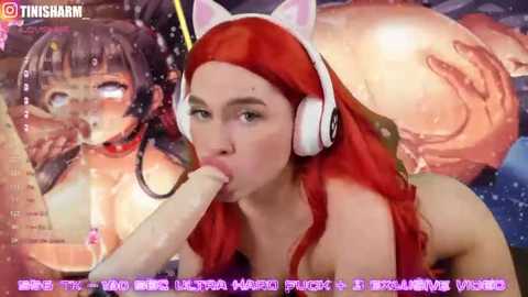 Media: A digital anime-style video shows a red-haired woman with cat ears and large white headphones, performing oral sex on a large, erect penis. Background features anime characters, and text overlays with Japanese text.