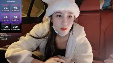 Media: A video of an Asian woman in a white hoodie and Santa hat, lying on a car seat, with a digital screen displaying her live stream stats.