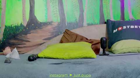 Media: Video of a bedroom with a green forest mural on the wall, featuring a brown pillow and a yellow pillow on a bed, with a black headset and a green pillow in the foreground.