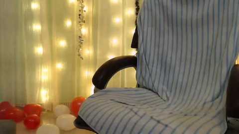 Media: A video shows a penguin-shaped chair covered in blue-striped fabric, surrounded by red and white balloons against a backdrop of soft, glowing fairy lights.