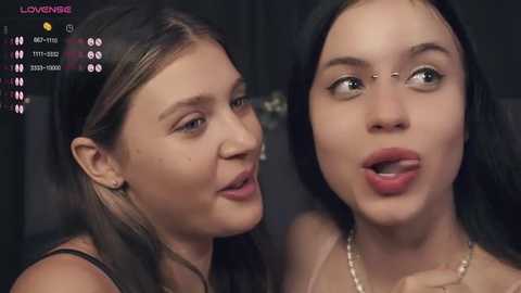 Media: A video features two young women with fair skin, one with long dark hair and a nose piercing, the other with straight black hair and a nose stud, both smiling.