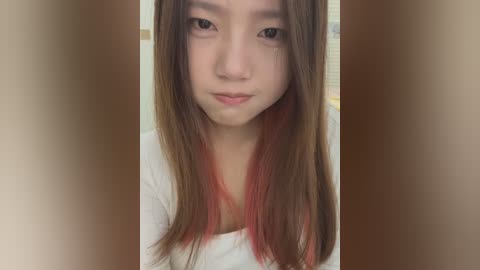 Media: Video of an Asian woman with straight, shoulder-length hair featuring a vibrant red ombre, light skin, and a neutral expression, wearing a white top.