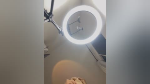 Media: Video of a ceiling with a circular, bright white light fixture and a blurred, beige ceiling fan, captured from a low angle.