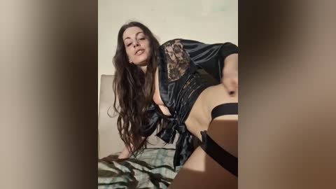 Media: A video shows a fair-skinned woman with long, wavy brown hair, wearing a black satin robe with leopard print, revealing her black thong and garter belt. She leans seductively on a bed with green sheets in a dimly lit room.