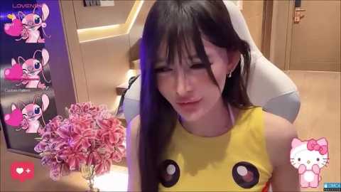 Media: A video shows an Asian woman with long black hair, wearing a yellow Pikachu dress, sitting on a white chair in a modern room.