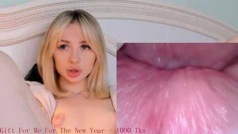 Media: Video of a young, fair-skinned, blonde woman with straight hair, lying on a white bed with a fancy headboard, showing her bare breasts and a close-up of her pink inner labia.