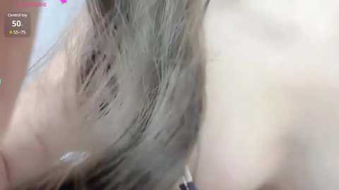 Media: A close-up video of a person's head, focusing on their messy, light-colored hair. The background is blurred, with a caption indicating \"Competition\" and \"50%\". The image appears to be taken from a video feed.