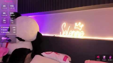 Media: A video shows a person in a black and white Mickey Mouse costume, facing a wall with a glowing \"Welcome\" sign. The background includes a TV screen with various digital elements, and a dark, textured wall.