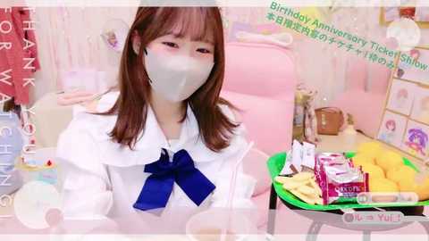 Media: Video of a young woman with straight brown hair, wearing a white blouse with a blue bow, mask, and a tray of food in a pink-themed room.