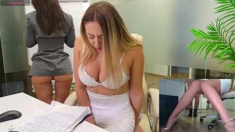 Media: Video of a woman in a white lingerie set, bending over a desk, while another woman, partially visible, stands behind her.