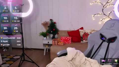 Media: Video of a cozy, festive living room with a beige couch, red pillows, Christmas decorations, and a \"LOOTBEE\" gaming chair.