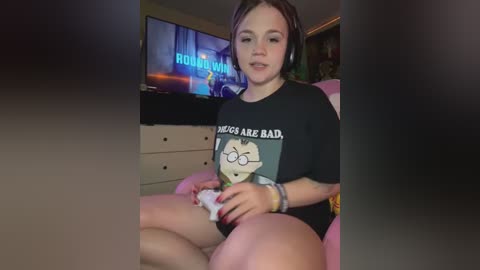 Media: Video of a young woman with light skin, brown hair, and glasses, wearing a black \"Rick and Morty\" T-shirt, playing a video game on a console, in a dimly lit living room.