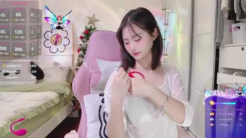 Media: A video of a young Asian woman with fair skin and shoulder-length black hair, wearing a sheer white top, applying red lipstick in a modern, brightly-lit bedroom.