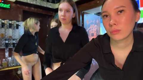 Media: Video of four women in a dimly-lit bar, wearing black tops and no pants, appearing casual and relaxed.