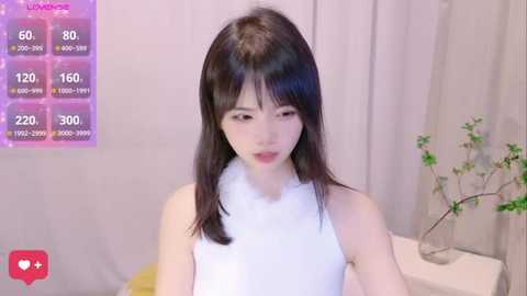 Media: Video of an Asian woman with straight black hair and pale skin, wearing a white sleeveless top. Background features a pinkish-purple digital overlay with stats, a plant, and beige curtains.