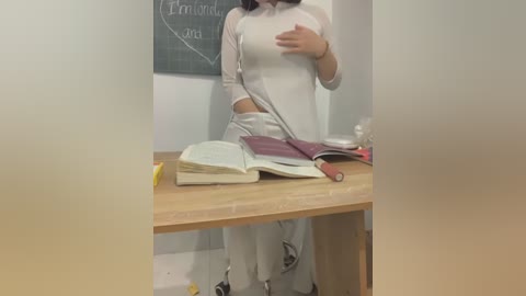 Media: A video of a person in a white lab coat, holding an open book, standing in front of a wooden desk with scattered papers, against a chalkboard background.