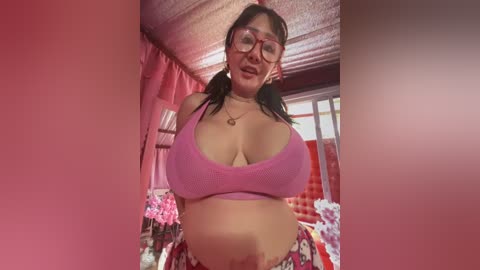 Media: A video of an Asian woman with large breasts wearing a pink crop top and floral shorts, smiling in a pink-themed room with heart-shaped decorations.