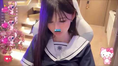 Media: A video of a young Asian woman in a sailor school uniform, sitting on a white gaming chair, with a virtual overlay of a pink cat and heart emojis.