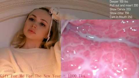 Media: A video of a blonde woman with fair skin, wearing a beige sweater, lying on a white bed with a pink, textured, inner ear view in the background.