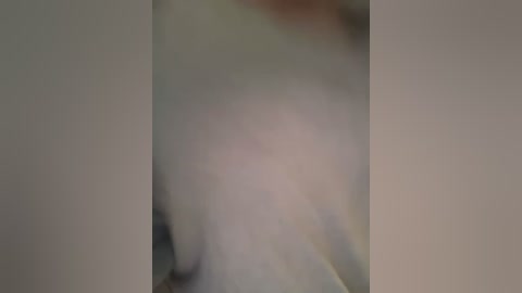 Media: A blurred video featuring a person's upper body, partially obscured by a soft, out-of-focus light. The image suggests a white shirt and possibly a hint of a dark background, but overall details are indiscernible.