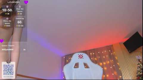 Media: Video of a woman in a revealing black outfit with a large, white, skull-themed gaming chair against a warm, glowing background with fairy lights and a TV.