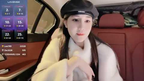 Media: Video of a young Asian woman with fair skin, long black hair, and a black beret, sitting in a red leather car seat, wearing a white fur coat.