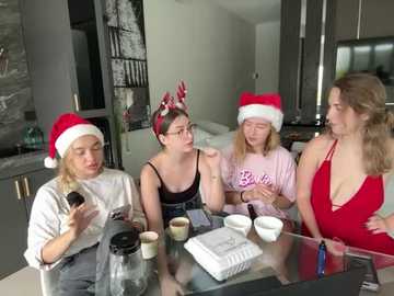 Media: Video of four young women in a modern kitchen, wearing festive Santa hats and casual clothes, making coffee, chatting, and smiling.