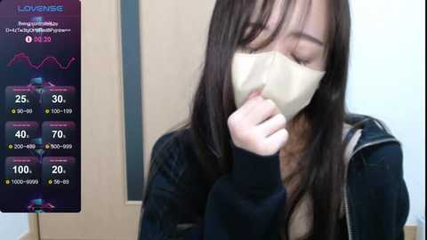 Media: Video of a young Asian woman with long black hair and a white mask, wearing a black hoodie, in a room with a graph showing \"Lovingness\" and \"Purity.\