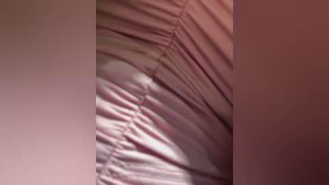 Media: Close-up video of a person's leg and thigh covered in soft, pastel pink satin fabric with subtle creases, creating a luxurious texture.