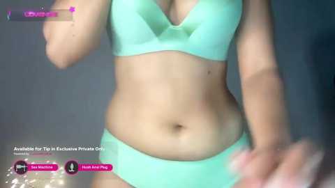 Media: Video of a light-skinned woman in a mint green bra and matching panties, standing indoors, with blurred background. Text overlays include \"Hate Live\" and \"Hi, Honey.\