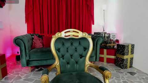 Media: Video of a plush, green velvet chair with gold accents, facing a red curtain backdrop and gift-wrapped presents on a tiled floor.