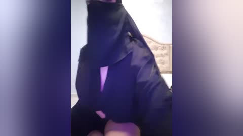 Media: Video of a person wearing a black jacket, standing indoors against a blurred background. The image is slightly out of focus, emphasizing the jacket's texture and the person's stance.