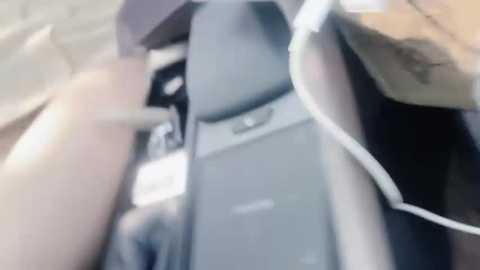 Media: A blurry video of a person's head and upper torso, wearing headphones, seated in a car with a dark-colored car seat and visible steering wheel.